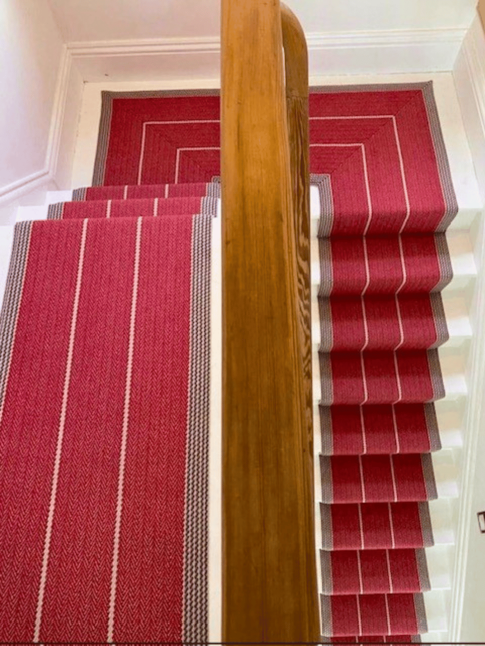 Roger Oats Stairs Carpet - red carpet with white lines down white stairs in modern home.